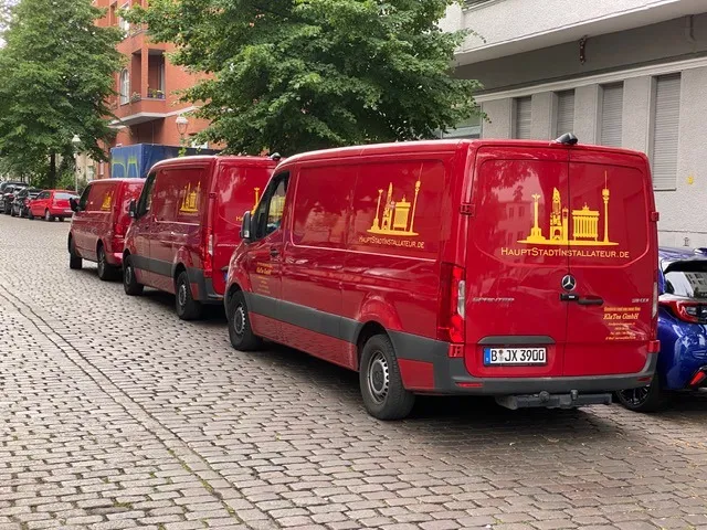 Drei rote Sprinter der KlaTes GmbH mit dem Logo Hauptstadtinstallateur auf Seite und Hecktüren, geparkt in einer Berliner Straße.
